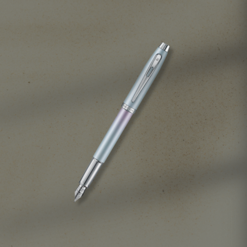 Slanted fountain pen with a silver nib on a textured beige surface, gradient barrel in pale blue and lavender colors.