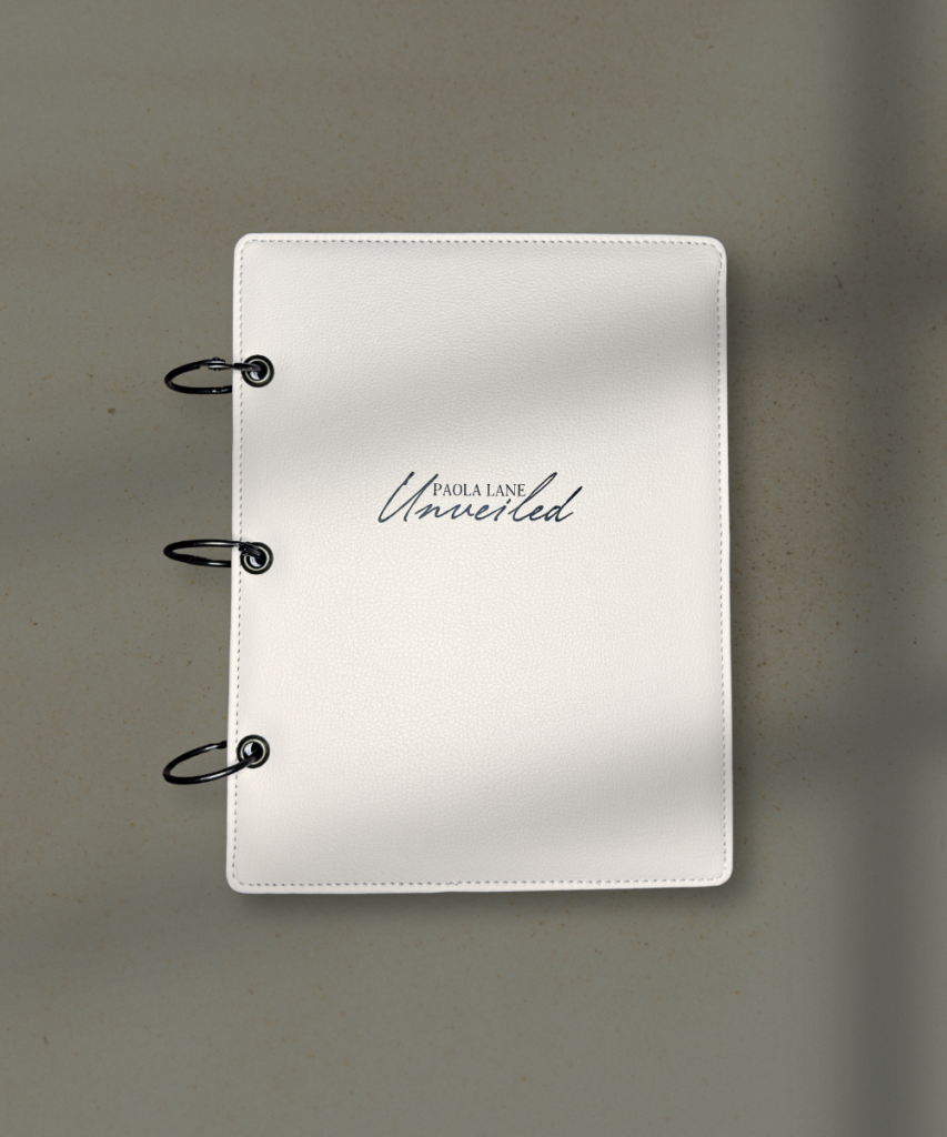 White leather binder with three metal rings on a beige surface; cover shows 'Paola Lane Untitled' in cursive.